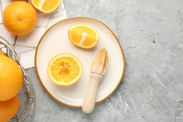 Wooden juicer and fresh oranges on grey table, flat lay. Space for text