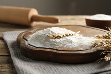 Wheat flour, spikelets and rolling pin on wooden table, closeup