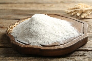 Wheat flour and spikelets on wooden table, closeup