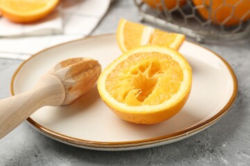 Wooden juicer and fresh oranges on grey table, closeup