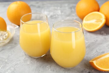 Orange juice in glasses and fresh fruits on grey table, closeup