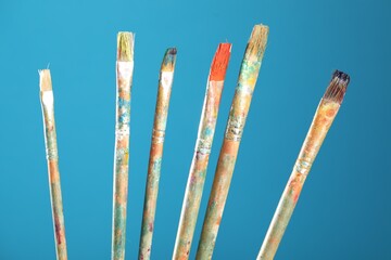 Dirty paintbrushes on light blue background, closeup