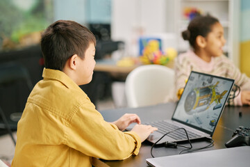 Children engrossed in educational activities involving laptop use in classroom setting, fostering an interactive learning environment with modern technology