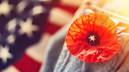 A red poppy on denim honors Memorial Day, with a flag softly behind, bathed in golden light. Remembrance and patriotism in a simple symbol.