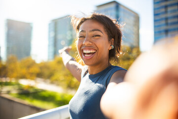 young woman in t-shirt smiling and pointing toward the city skyline while taking selfie