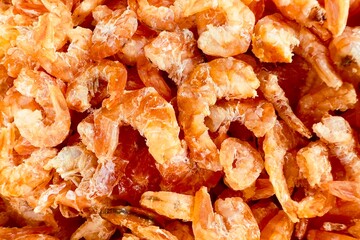 Close-up of dried shrimp. Small, pinkish-orange in color, they appear slightly translucent when cooked. Dried shrimp are often used as a seasoning or ingredient in various Asian dishes, adding a salty