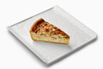 Slice of delicious salmon and broccoli quiche on white plate