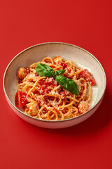 Delicious italian spaghetti with tomato sauce, basil, and cheese on red background