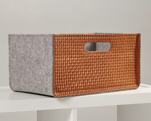 Woven leather and felt storage box sitting on white shelf
