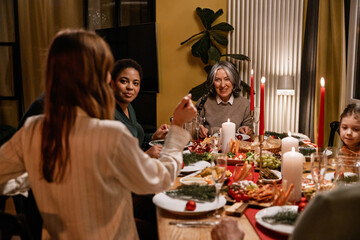 Family and guests sitting at a table and smiling while talking