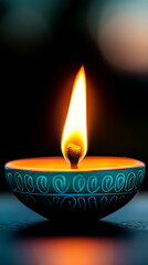Teal Diya with Bright Flame Against Dark Background