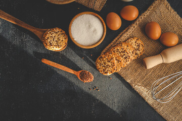 Top view of rustic baking ingredients including cookies with seeds, sugar, eggs, flaxseeds, and...