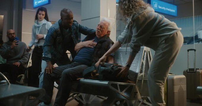 Crowded International Airport Terminal: Elderly Man Having Heart Attack, Infarction in Boarding Lounge of Airline Hub. Diverse People Helping Senior Passenger, Airport Worker Calling for Medical Help.