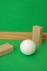 Still life with wooden blocks and a a plastic foam ball on green background	
