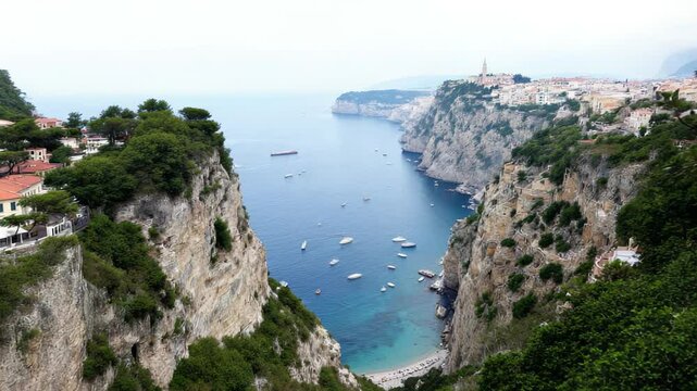 Steep rocky cliffs framing a bay filled with boats and blue water under soft light. Concept of coastal exploration and maritime adventure