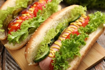 Tasty hot dogs with vegetables on wooden table, closeup