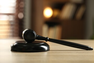 Judge's gavel on wooden table against blurred background, closeup