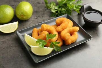 Tasty tempura shrimps, lime, parsley and soy sauce on grey textured table
