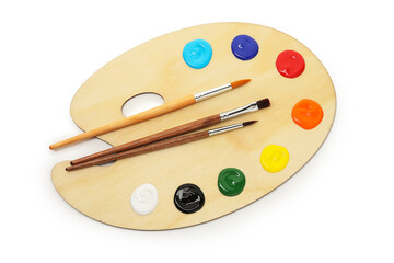 Wooden palette with paints and brushes isolated on white, top view