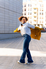 Happy cuban woman walking in the city wearing headphones and smiling
