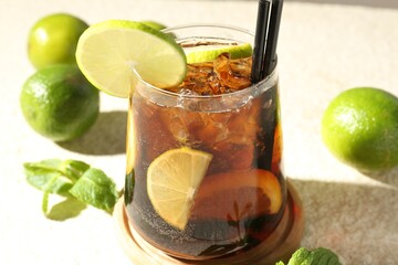 Tasty Cuba Libre cocktail in glass and ingredients on light textured table, closeup