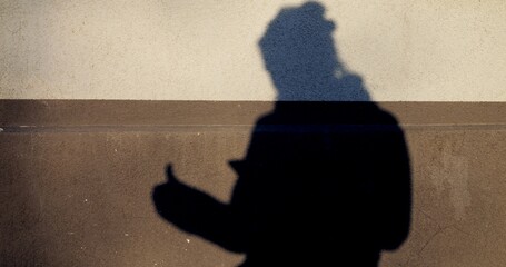 Shadow of a person casting thumbs up gesture on two tone wall, projecting nonverbal communication...