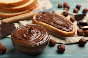 Toast with tasty chocolate hazelnut spread and nuts on blue wooden table, closeup