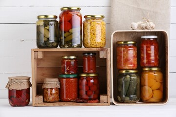 Many jars with different pickled products and ingredients on white wooden table
