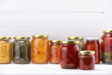 Many jars with different pickled products on white wooden table