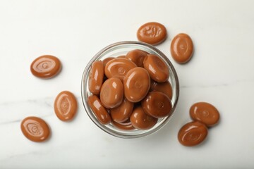 Many tasty caramel candies on white table, flat lay