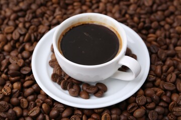 Fototapeta premium Aromatic coffee in cup, saucer and beans, closeup