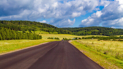 Beautiful summer landscape with asphalt road and blue sky with white clouds