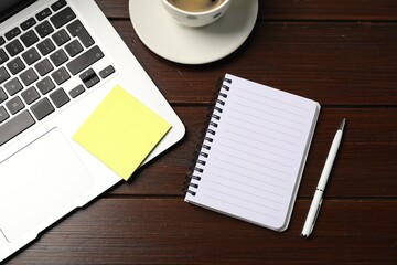 Notebook, sticky note, pen, coffee and laptop on wooden table, flat lay