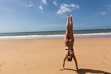 Mujer joven en la playa haciendo un ejercicio de yoga.