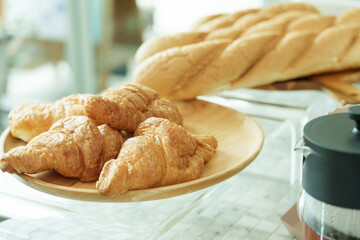Closeup of fresh croissants and baguettes displayed on plate inside cafe, representing warmth, charm, and artisanal appeal of small family coffee business with cozy atmosphere, Concept small business