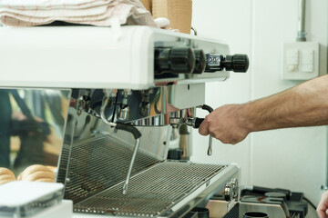 Adult male barista locking portafilter into espresso machine inside cafe, demonstrating artisan skill, precision, and dedication of small family coffee business, Concept small business