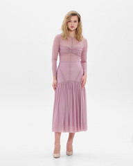 Girl model in pink dress on white studio background.