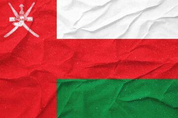 OMAN An artistic rendition of a crumpled flag, rendered in textured shades of red, white and green.