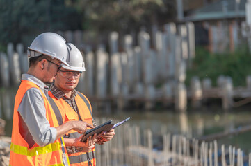 Construction engineer working on a bridge construction site over a river,Civil engineer supervising work,Foreman inspects work at a construction site,Discuss technical problems together