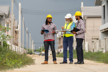 Structural engineer and worker working with blueprints discuss at the construction site. Engineers on building site. Two worker or labor and one engineer are reviewing the project. Architecture.