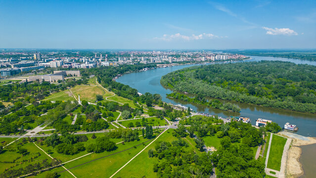 Aerial view of Belgrade where the Sava and Danube rivers meet. Visible landmarks include Kalemegdan Fortress (Beogradska tvrđava), city bridges, and U&scaron;će Park &mdash; a perfect urban-meets-nature panorama