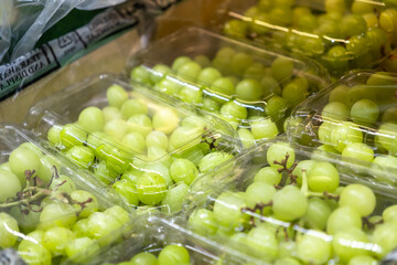 Green grapes in clear plastic containers on store display ideal for healthy snacking, quick snacks,...