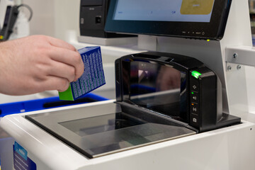 Scanning small packaged product item using automated self checkout technology at retail store station promoting quick independent transaction