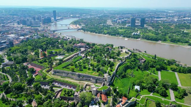 Aerial view of Belgrade where the Sava and Danube rivers meet. Visible landmarks include Kalemegdan Fortress (Beogradska tvrđava), city bridges, and U&scaron;će Park &mdash; a perfect urban-meets-nature panorama