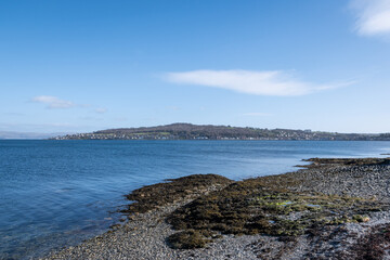 stunning rugged rocky Scottish coastline landscape from Bute island looking into the clear cold blue water Firth of Clyde on a gorgeous sunny day.