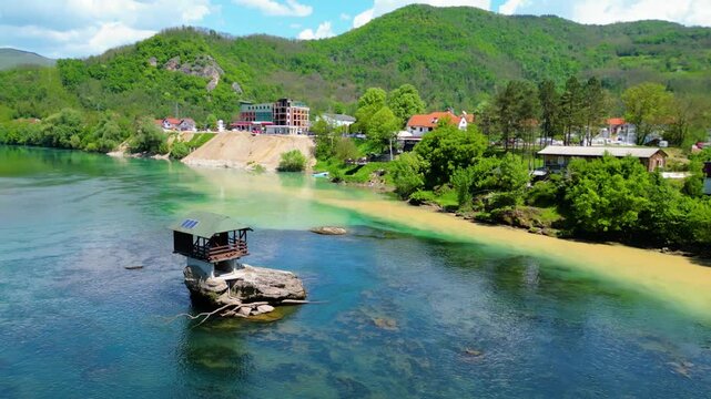 Aerial view of Bajina Ba&scaron;ta and the iconic Kućica na Drini (Drina River House), peacefully perched on a rock in the middle of the emerald Drina River, surrounded by lush nature and mountain landscapes
