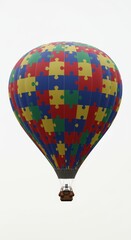 Fototapeta premium A colorful hot air balloon decorated with puzzle pieces against a white cloudy sky background view