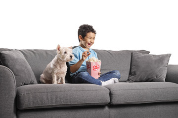 Boy and a dog sitting on a sofa and eating popcorn