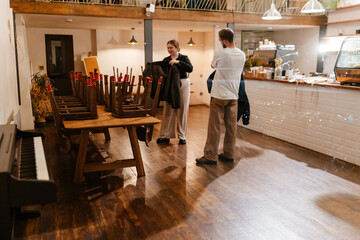 A female owner and a male employee are standing and getting dressed in outerwear, in a cafe