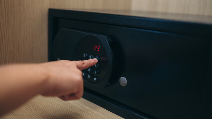 Close-up of a person hand entering a password to unlock and open the safe box door.